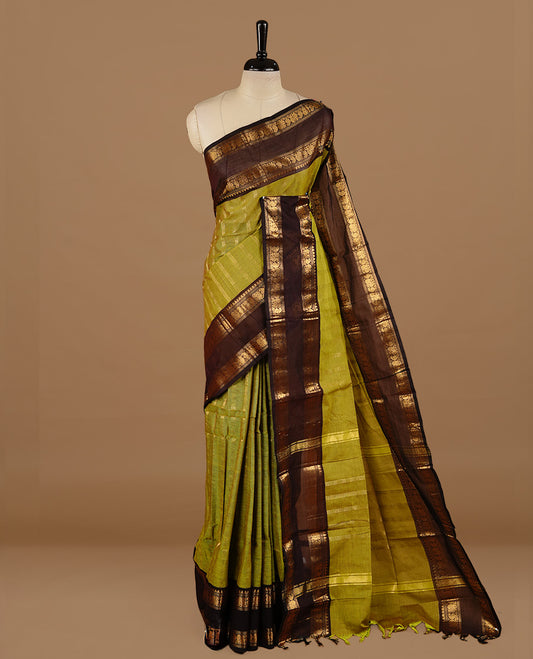 Olive colour chettinad cotton saree featuring gold zari stripes on body, complemented by dark chocolate colour with zari border, paired with matching blouse piece.