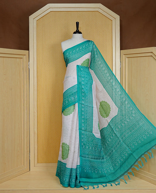 Cream colour semi linen saree featuring Light green Ajrakh pattern print on body, complemented by contrast green colour with same pattern print border, comes with matching blouse piece.
