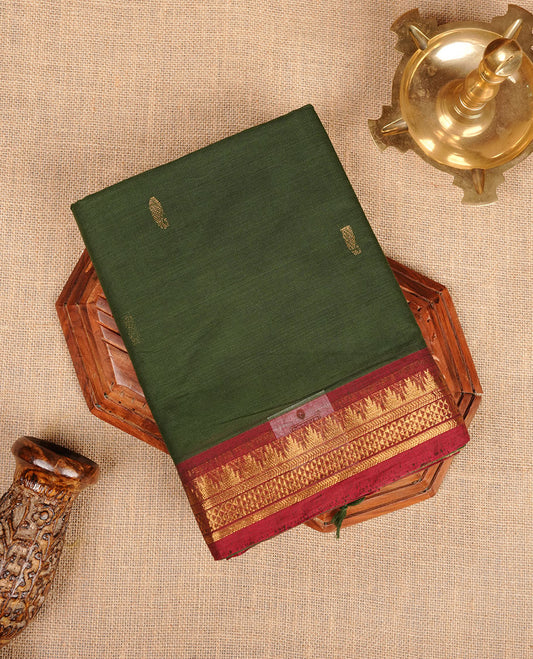 Dark green colour chettinad cotton saree featuring gold zari motifs on body, contrast Red colour with traditional gold zari border paired with matching blouse.