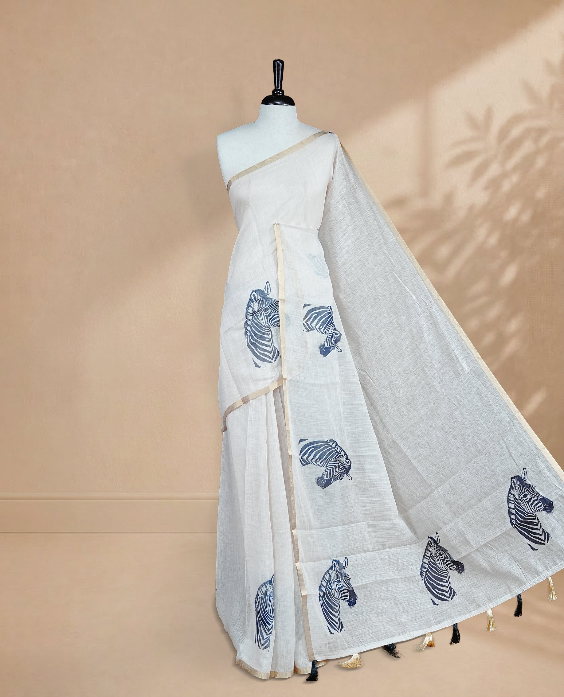 Cream semi linen saree featuring an elegant zebra print all over the body, highlighted with a delicate tissue border and paired with a matching blouse piece.