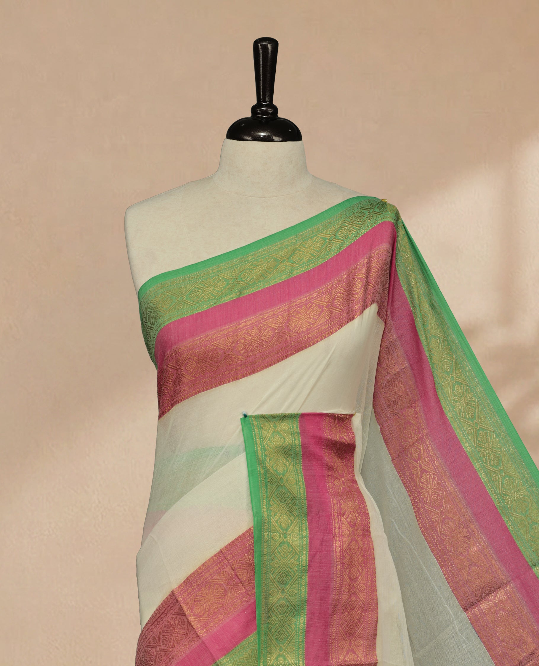 Off white Colour Mul Cotton saree featuring Elegant plain body, contrast Green & Pink colour with gold zari traditional border.
