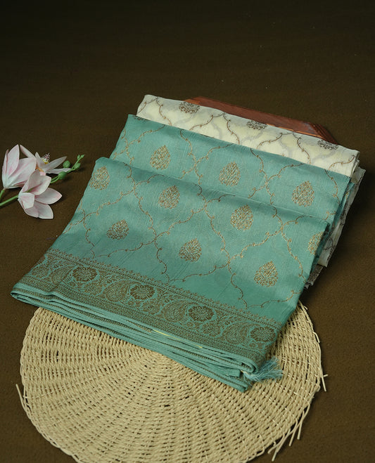 Cream colour semi tussar Banarasi saree featuring Antique zari motifs on body, paired by contrast pastel green colour border, and a matching blouse piece.