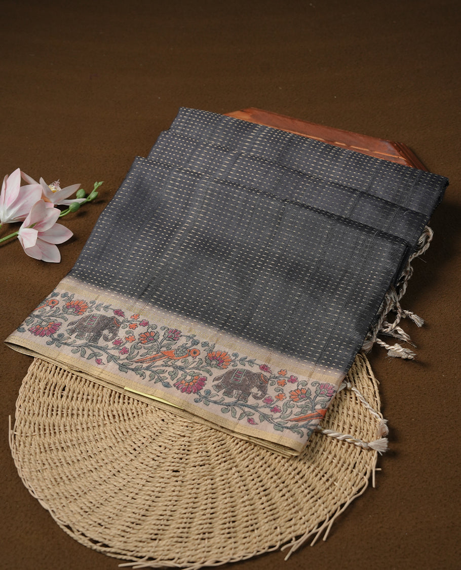 Charcoal black colour tussar saree featuring golden zari dot stripped pattern on the body, complemented by a contrast cream colour mutlicolour floral kodi & animal print on border & pallu, paired with a matching blouse.