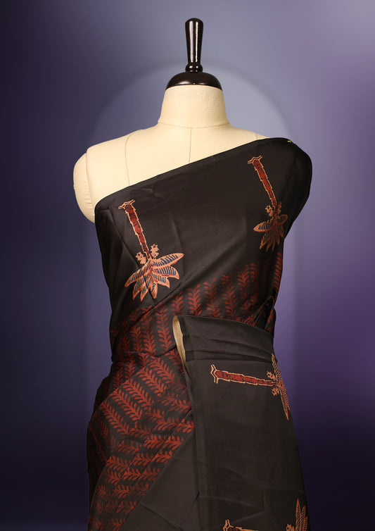 Black colour saree beautifully embellished with brick red woven palm tree and geometric motifs, featuring a rich patterned border and pallu, paired with a matching blouse.