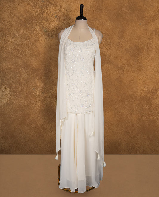 Ivory white colour sharara set featuring delicate sequin and thread floral embroidery across the body, a soft scoop neckline, and a flowy sharara silhouette, paired with a sheer matching dupatta.