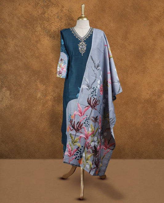 Teal blue colour churidar set featuring V neckline, half sleeves, and embellished floral embroidery on body, paired with a contrasting grey floral printed dupatta.