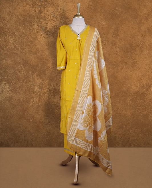 Mustard yellow churidar set featuring V neckline, elbow sleeves, and subtle sequin buttis on body, paired with a coordinated printed dupatta.