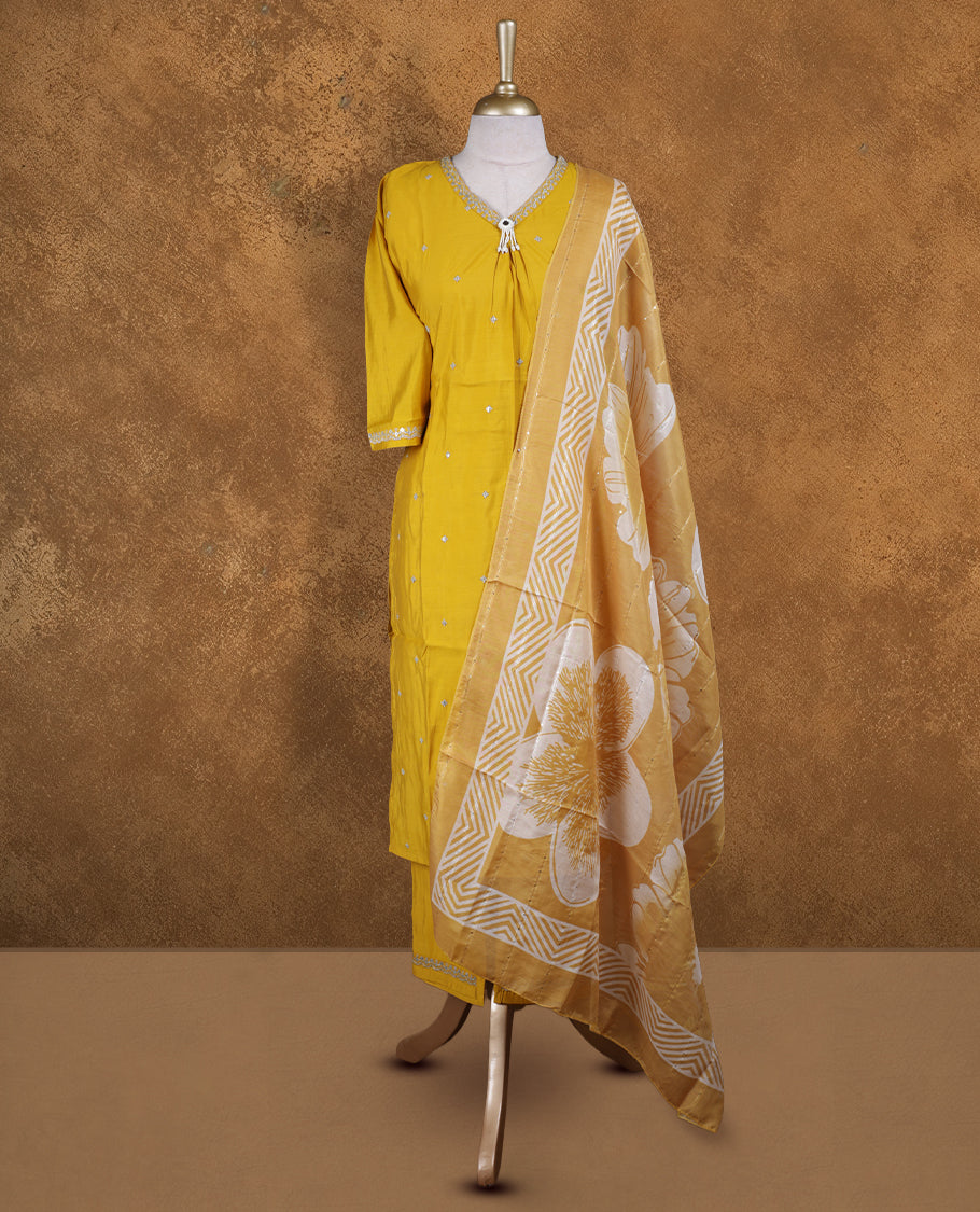 Mustard yellow churidar set featuring V neckline, elbow sleeves, and subtle sequin buttis on body, paired with a coordinated printed dupatta.