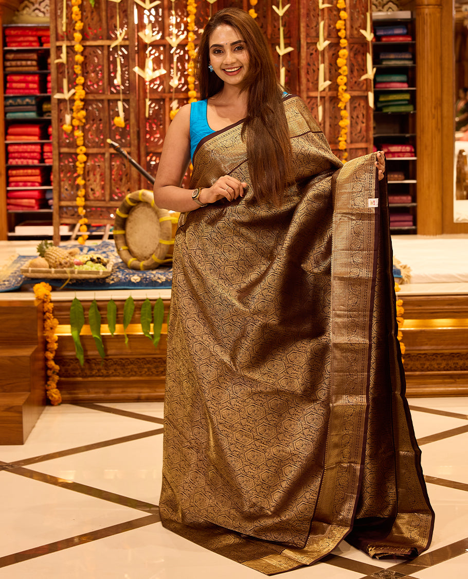 Dark chocolate colour Kancheepuram silk saree featuring intricate gold zari geometric and floral weaving throughout, completed with a rich gold zari border and grand pallu, paired with a matching blouse