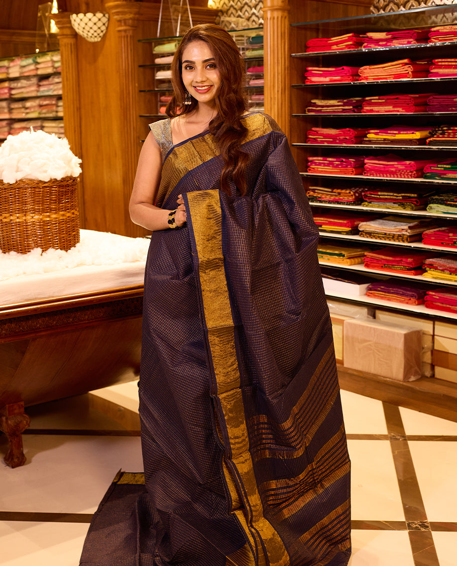 Deep navy blue colour silk cotton saree, featuring a subtle micro checkered body with rich gold zari borders and pallu, paired with a matching blouse piece
