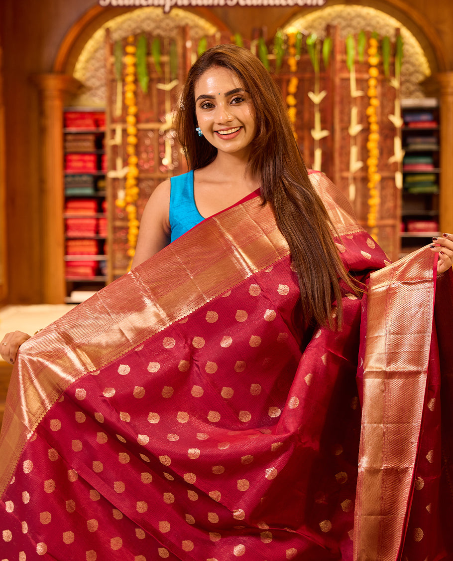 Wine colour Kancheepuram silk saree with classic gold zari polka motifs all over, complemented by a lustrous gold zari border and pallu, and paired with a matching blouse.