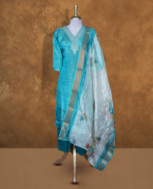 Aqua blue churidar set featuring a V-neckline with delicate thread and sequin embroidery, paired with a contrasting sheer floral-printed dupatta.