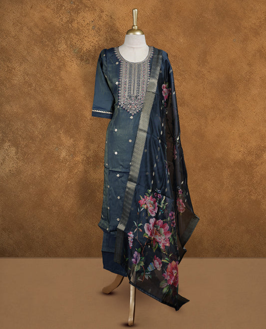 Dark grey blue churidar set featuring round neckline, elbow sleeves, and intricate embroidered yoke with scattered buttis, paired with a sheer floral printed dupatta.