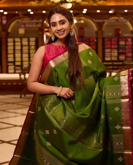 Vibrant parrot green colour Kancheepuram silk saree adorned with delicate gold zari motifs across the body, beautifully complemented by a classic zari border with hints of contrast, styled with a blouse
