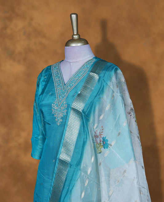 Aqua blue churidar set featuring a V-neckline with delicate thread and sequin embroidery, paired with a contrasting sheer floral-printed dupatta.