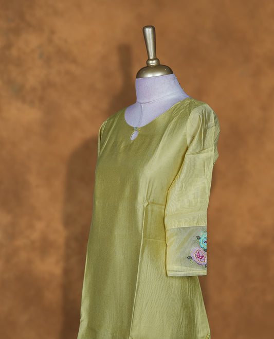 Pistachio green solid kurti featuring a round neckline with a subtle keyhole detail, a straight calf-length silhouette, and three-quarter sleeves highlighted with delicate floral embroidery.