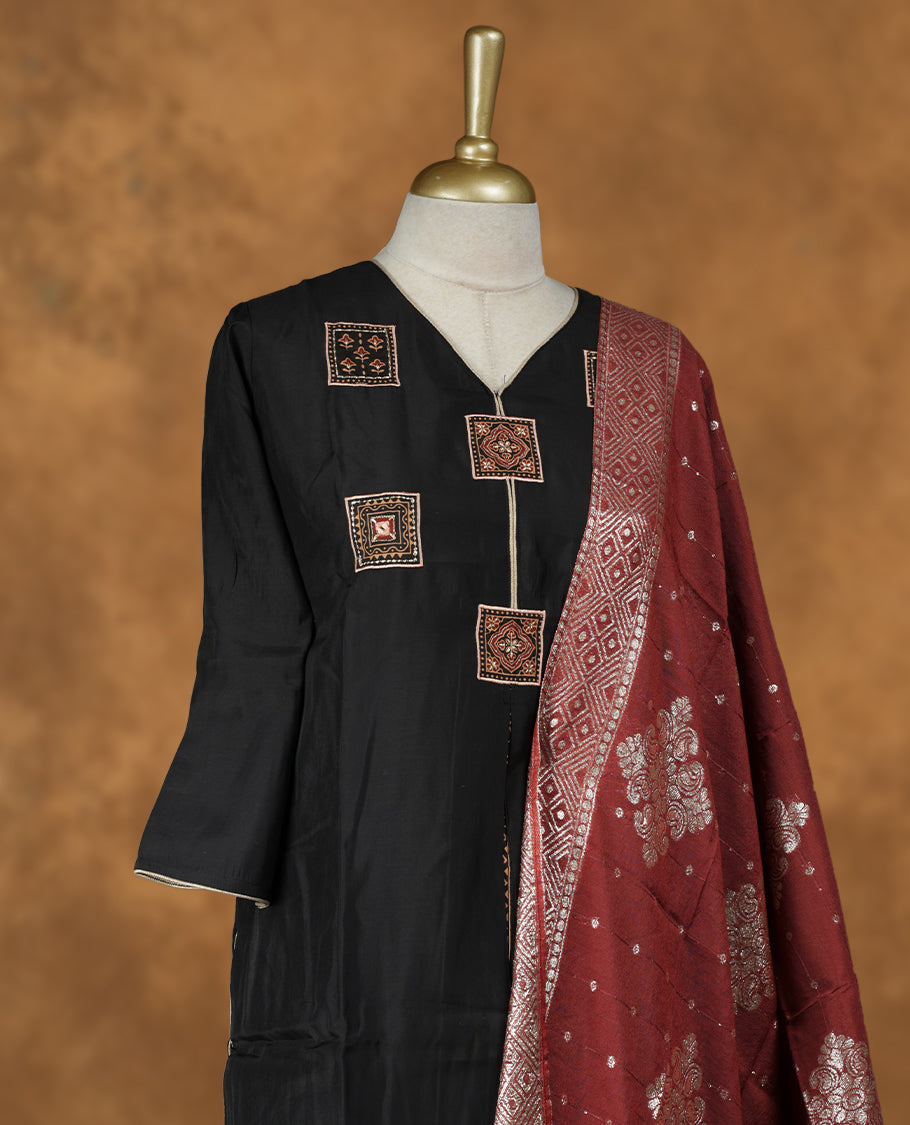 Black colour churidar set featuring thread embroidered pattern neckline, sleeves, and body , Paired with a contrast brick red colour dupatta