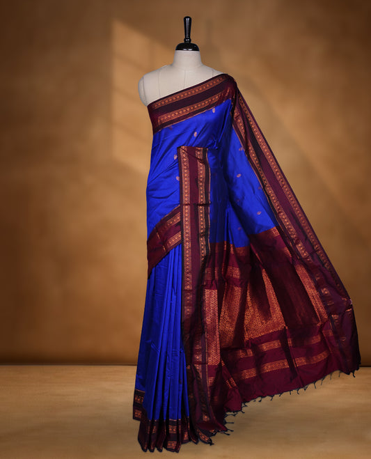 Royal blue colour saree with subtle zari motifs, complemented by a rich maroon zari border and traditional pallu, paired with a matching blouse.