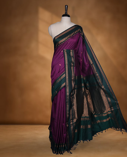 Purple colour mixed Kalyani cotton saree with subtle zari motifs, dark green zari border and rich traditional pallu, paired with a matching blouse.