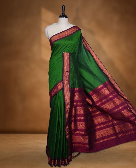 Green colour Kalyani cotton saree featuring a plain elegant body, complemented by a rich maroon zari border and traditional woven pallu, paired with a matching blouse.