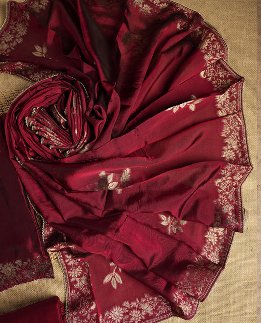 Elegant maroon colour suit material adorned with exquisite zari floral weaving, exuding regal charm & paired with a beautifully bordered dupatta and a matching plain bottom.