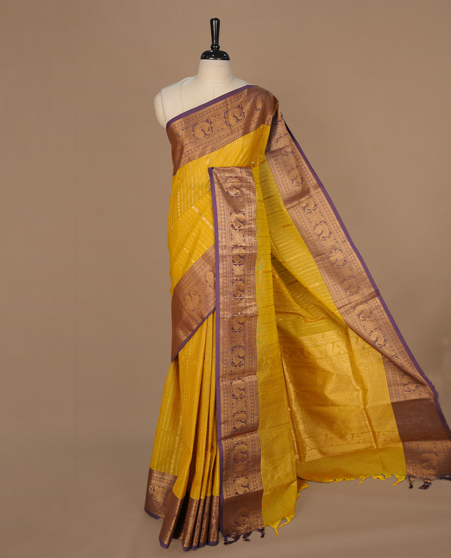 Olive yellow colour chettinad saree featuring gold zari motifs on body, complemented by contrast purple colour with traditional border, paired with matching blouse piece.
