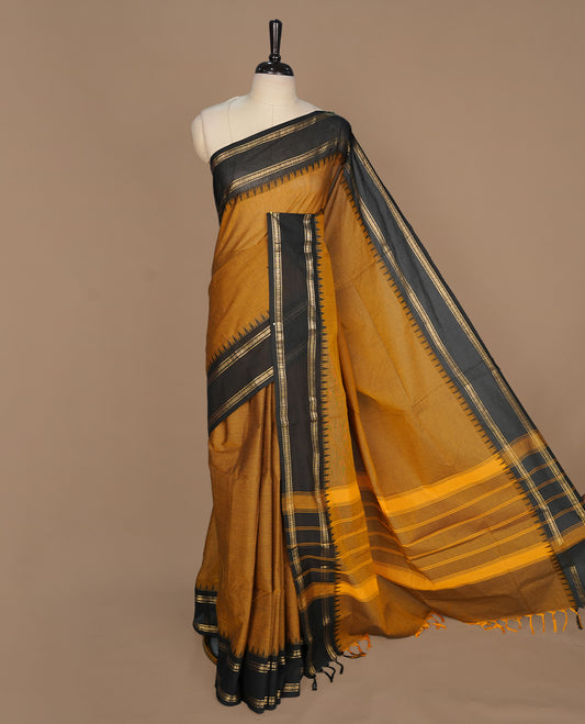 Bronze colour chettinad cotton saree featuring elegant plain body, complemented by contrast black with gold zari border, paired with matching blouse piece.