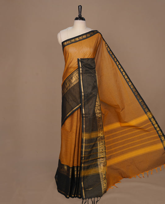 Mustard colour chettinad cotton saree featuring elegant plain body, complemented by contrast black colour with traditional border, paired with matching blouse piece.