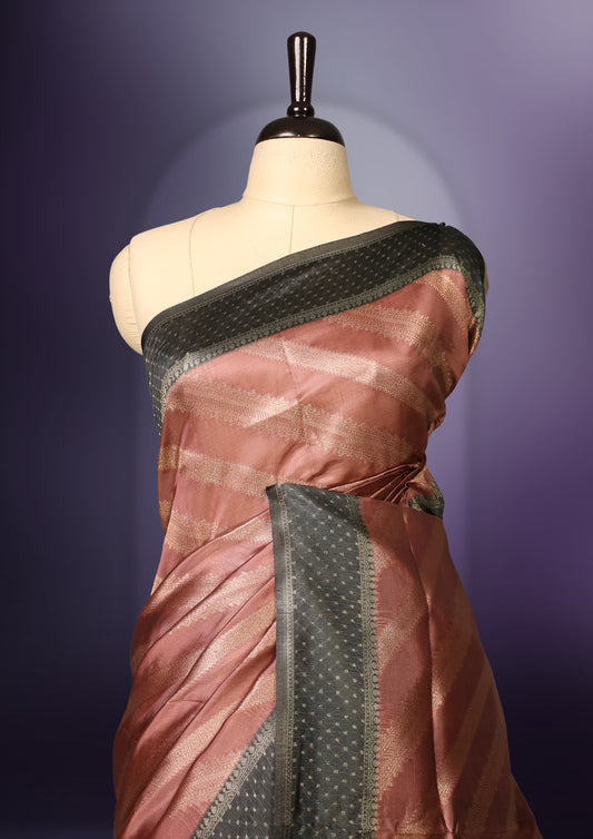 Golden Peach colour saree featuring subtle self striped woven patterns on the body, enhanced with a olive green geometric border, complemented by a rich zari pallu with tassels, and paired with a matching blouse for a traditional elegant look.