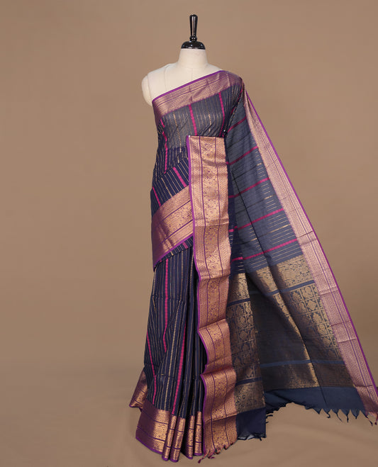 Navy blue colour chettinad saree featuring gold zari stripes on body, complemented by contrast Purple colour with traditional border, paired with matching blouse piece.