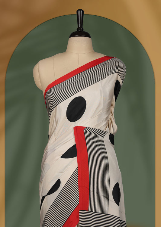 Cream colour saree with bold black polka dots, striped detailing, and striking red border & Comes with a stylish matching blouse.