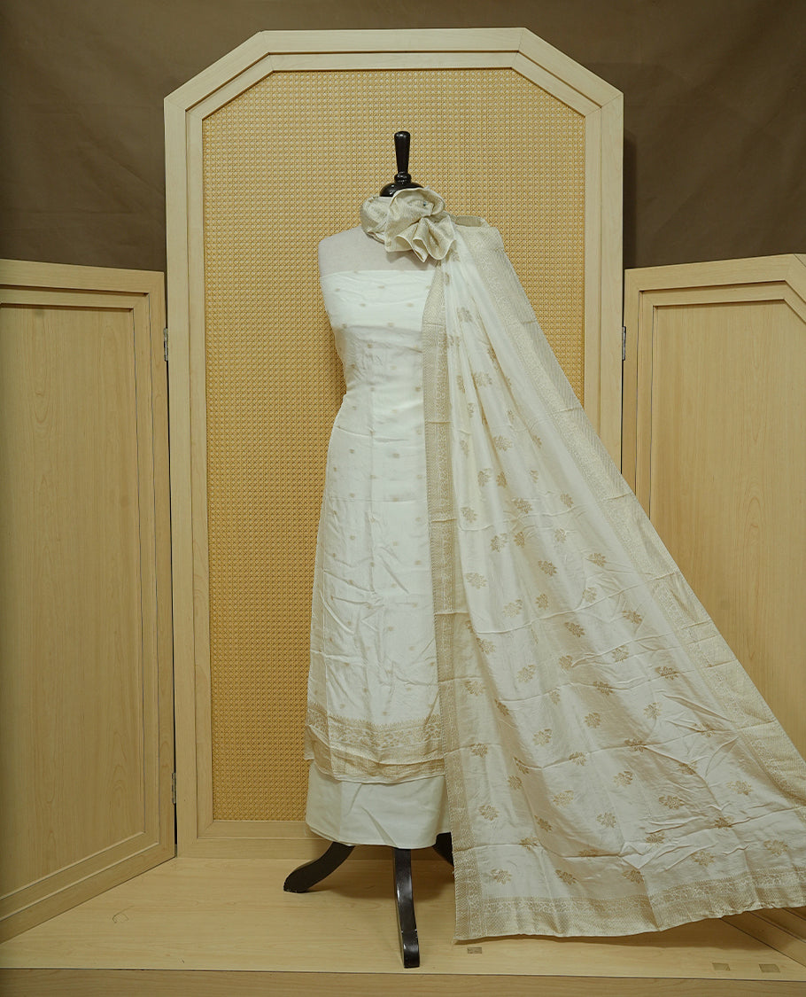 Cream colour Salwar material featuring gold zari Buttas on body, paired with matching dupatta & Bottom.