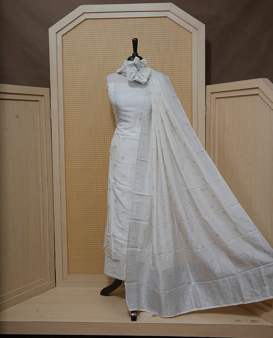 Cream colour Salwar material featuring silver zari Buttas on body & zari worked Neck Portion, paired with matching dupatta & Bottom.