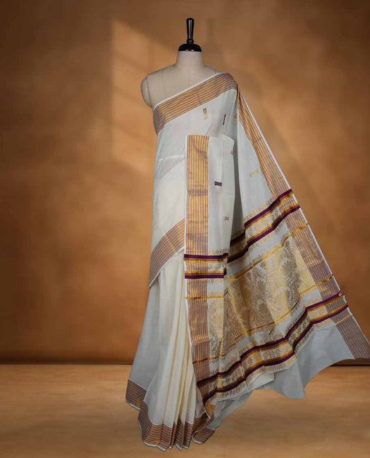 Off white Kerala saree with subtle woven motifs, striped zari border with purple accents, and rich traditional zari pallu, paired with a matching blouse.
