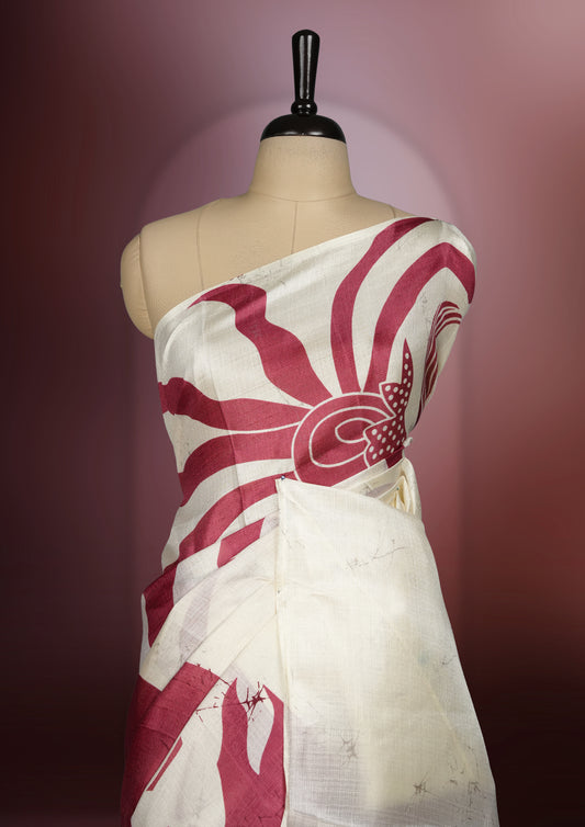 Cream and maroon colour saree with bold abstract floral patterns and a striking pallu design, blending modern artistry with traditional charm, paired with a matching blouse.