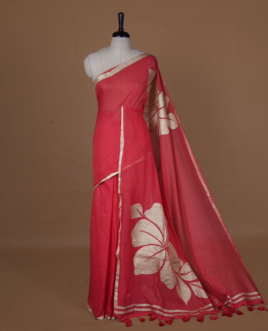 Red coloured mul cotton saree featuring bold gold-tone floral motifs across the body, designed without a border and comes without a blouse piece.
