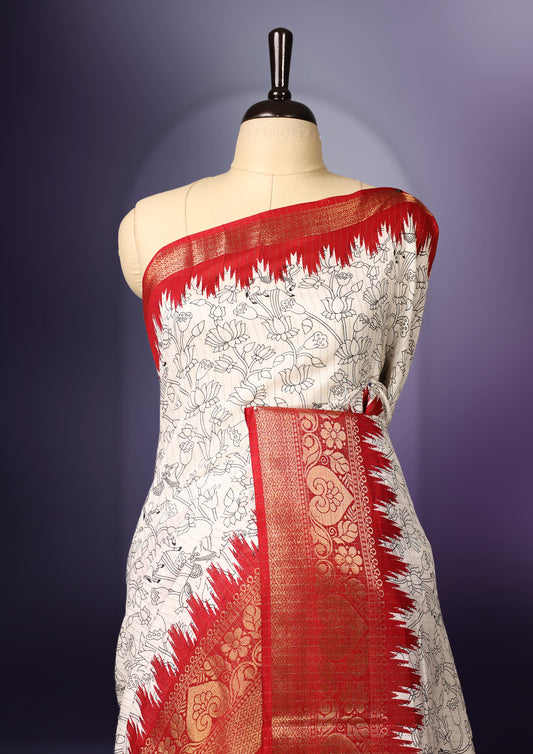 White colour  saree adorned with delicate black floral prints across the body, enhanced by a rich red and gold zari border, featuring a vibrant artistic pallu with traditional motifs, paired with a matching blouse.