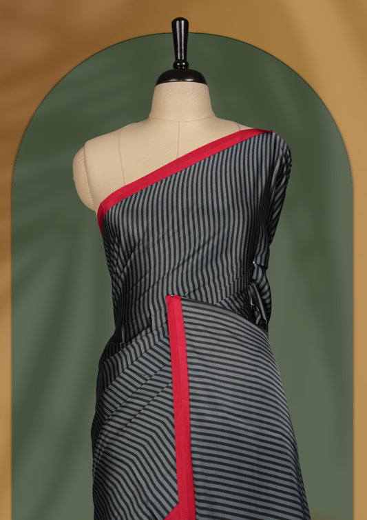 Black colour striped saree highlighted with a bold maroon border, featuring a striking pallu adorned with off white triangular patterns and intricate mandala style embroidery & Paired with a matching blouse.
