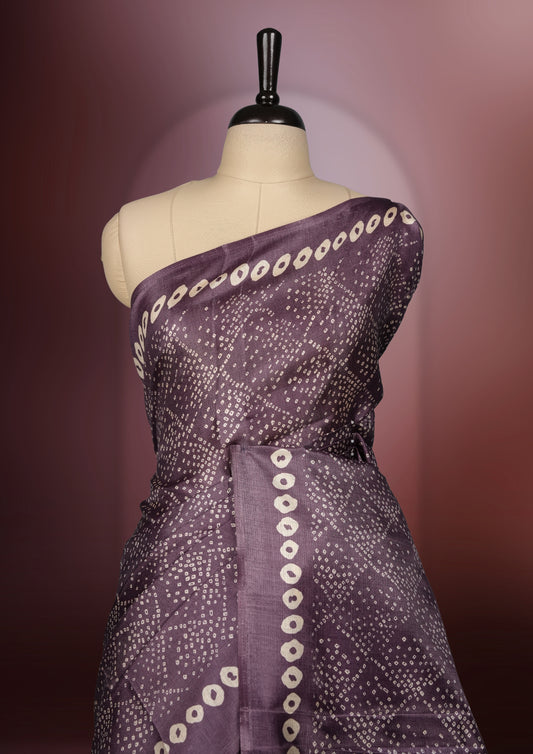 Light Wine colour saree adorned with intricate beige bandhani patterns and a contrasting pallu featuring exquisite beige floral motifs, perfectly paired with a matching blouse for a regal look.