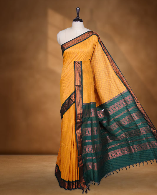 Mustard yellow colour mixed kalyani cotton saree featuring fine checked body, complemented by a dark green zari border and richly woven traditional pallu, paired with a matching blouse.