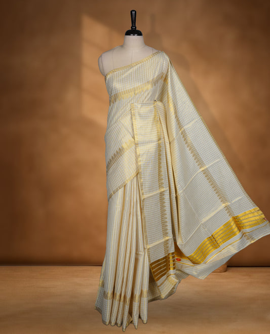 Off white colour Tissue Kerala saree featuring a fine striped and checked body, complemented by a classic golden zari border and traditional pallu design, paired with a matching blouse.