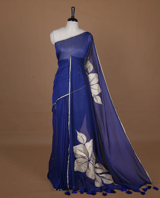Blue coloured mul cotton saree featuring bold gold-tone floral motifs across the body, designed without a border and comes without a blouse piece.