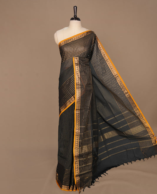 Black colour chettinad cotton saree featuring gold zari stripes on body, complemented by yellow piping with gold zari border, paired with matching blouse piece.