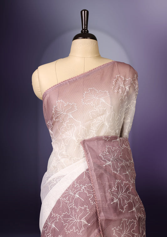 White and mauve shaded saree adorned with delicate floral threadwork across the body and border, featuring a soft ombre effect for an elegant appeal, paired with a matching blouse.