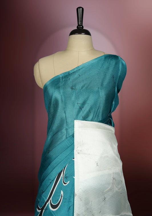 Teal blue colour saree adorned with bold off white floral prints, blending tradition with a modern twist & paired with a matching blouse.