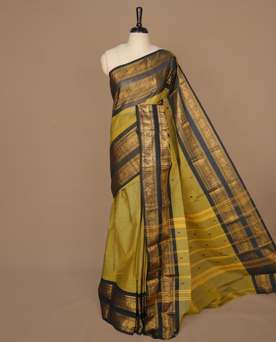 Olive colour chettinad saree featuring gold zari motifs on body, complemented by contrast black colour with traditional border, paired with matching blouse piece.