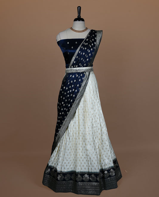 Off white semi banaras semi stitched dhavani set featuring gold zari motifs and contrast Teal colour and traditional border, unstitched gold zari blouse piece and matching Duptta.