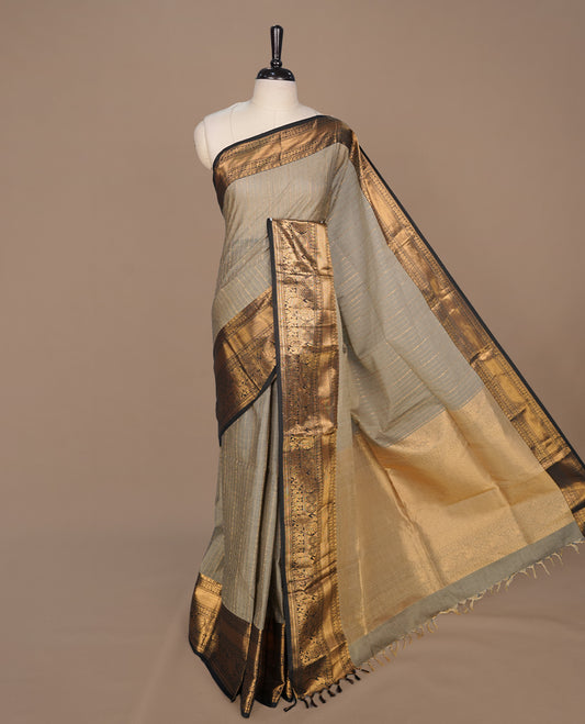 Grey colour chettinad cotton saree featuring gold zari stripes on body, complemented by contrast black colour with gold zari border, paired with matching blouse piece.