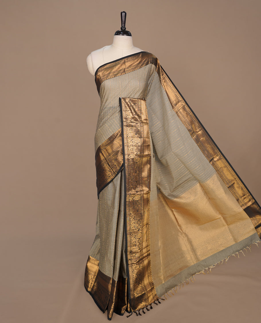 Grey colour chettinad cotton saree featuring gold zari stripes on body, complemented by contrast black colour with gold zari border, paired with matching blouse piece.
