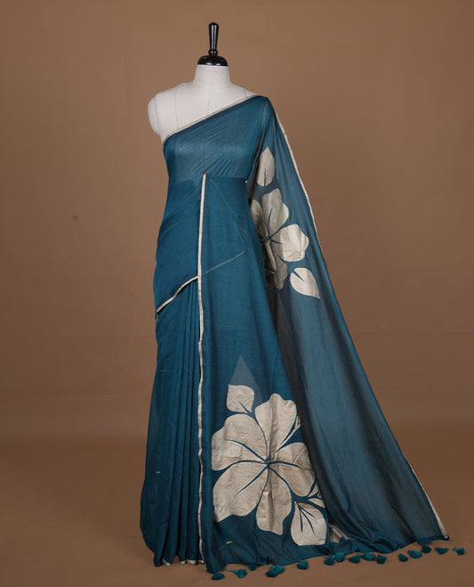 Green coloured mul cotton saree featuring bold gold-tone floral motifs across the body, designed without a border and comes without a blouse piece.